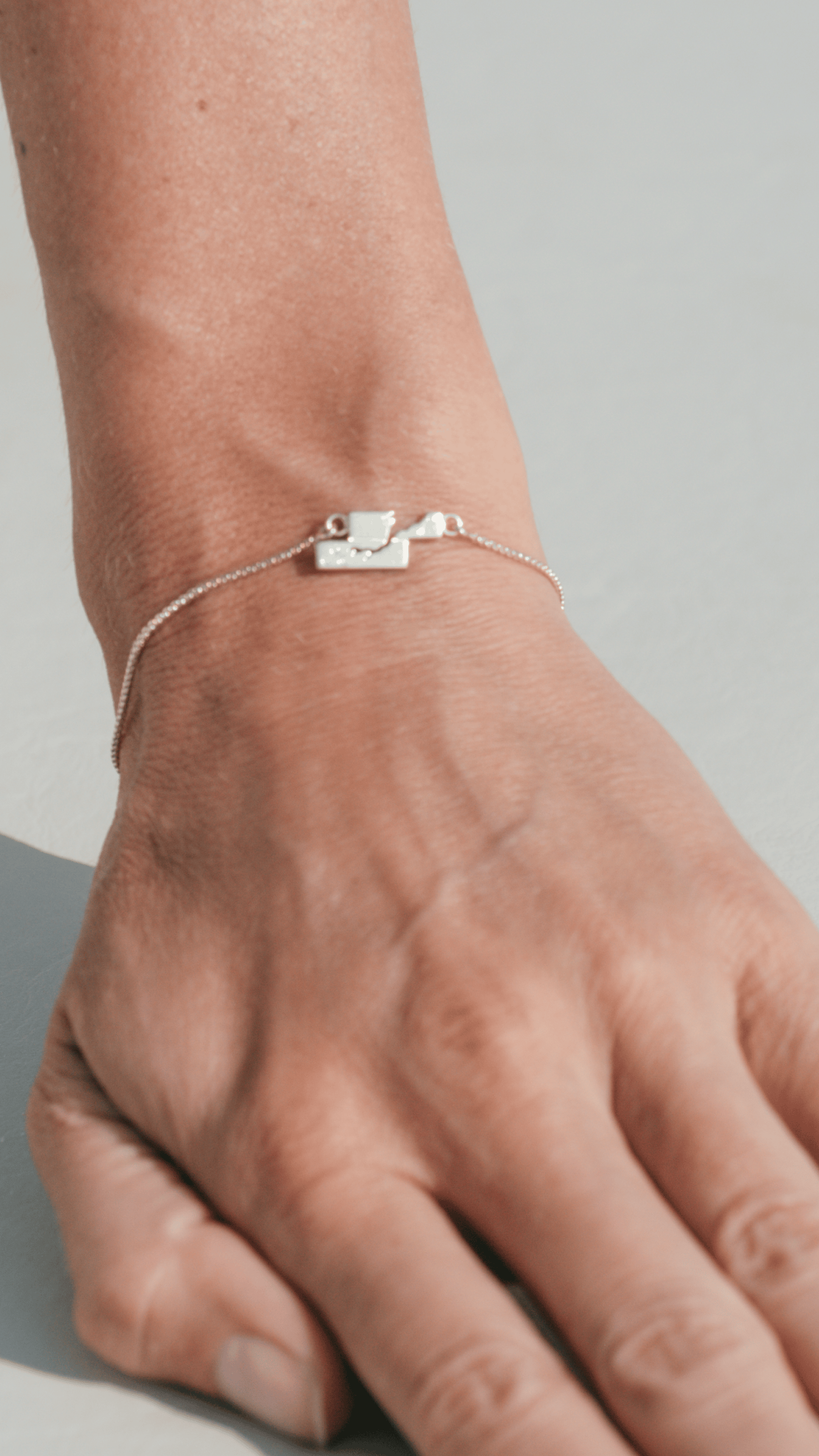 Silver bracelet on a wrist against a neutral background