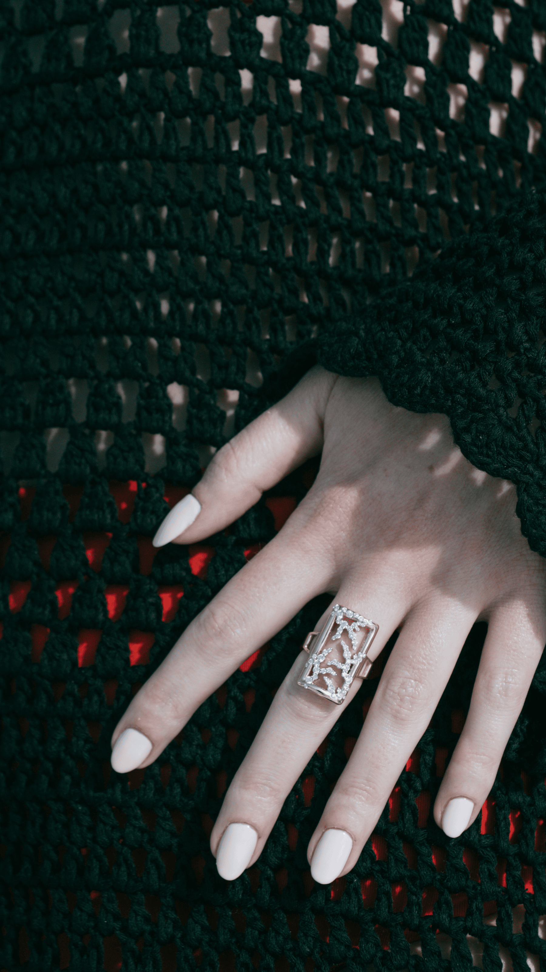 Hand wearing a ring with a textured dark background