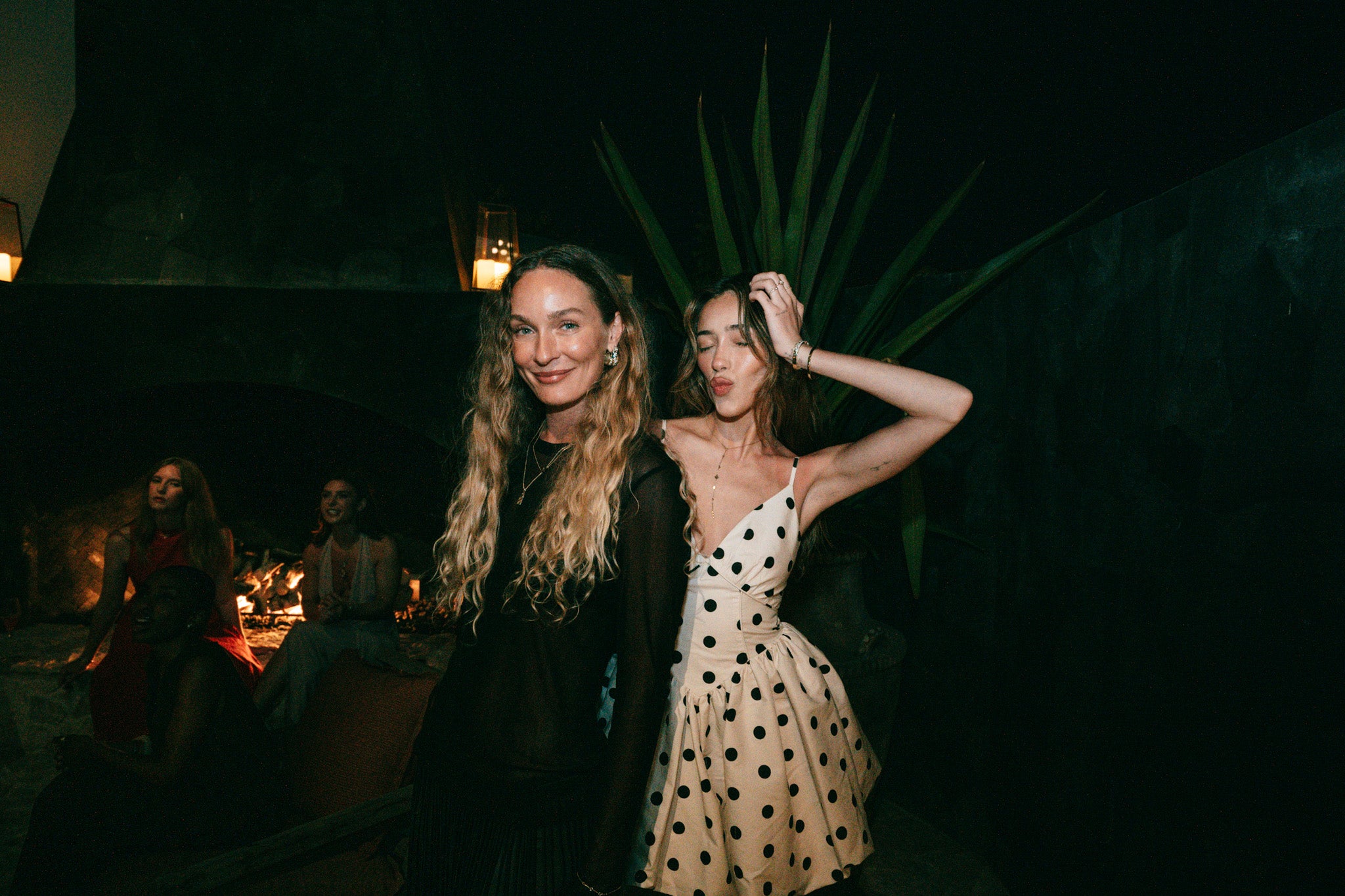 Two women standing outdoors at night with a dark background