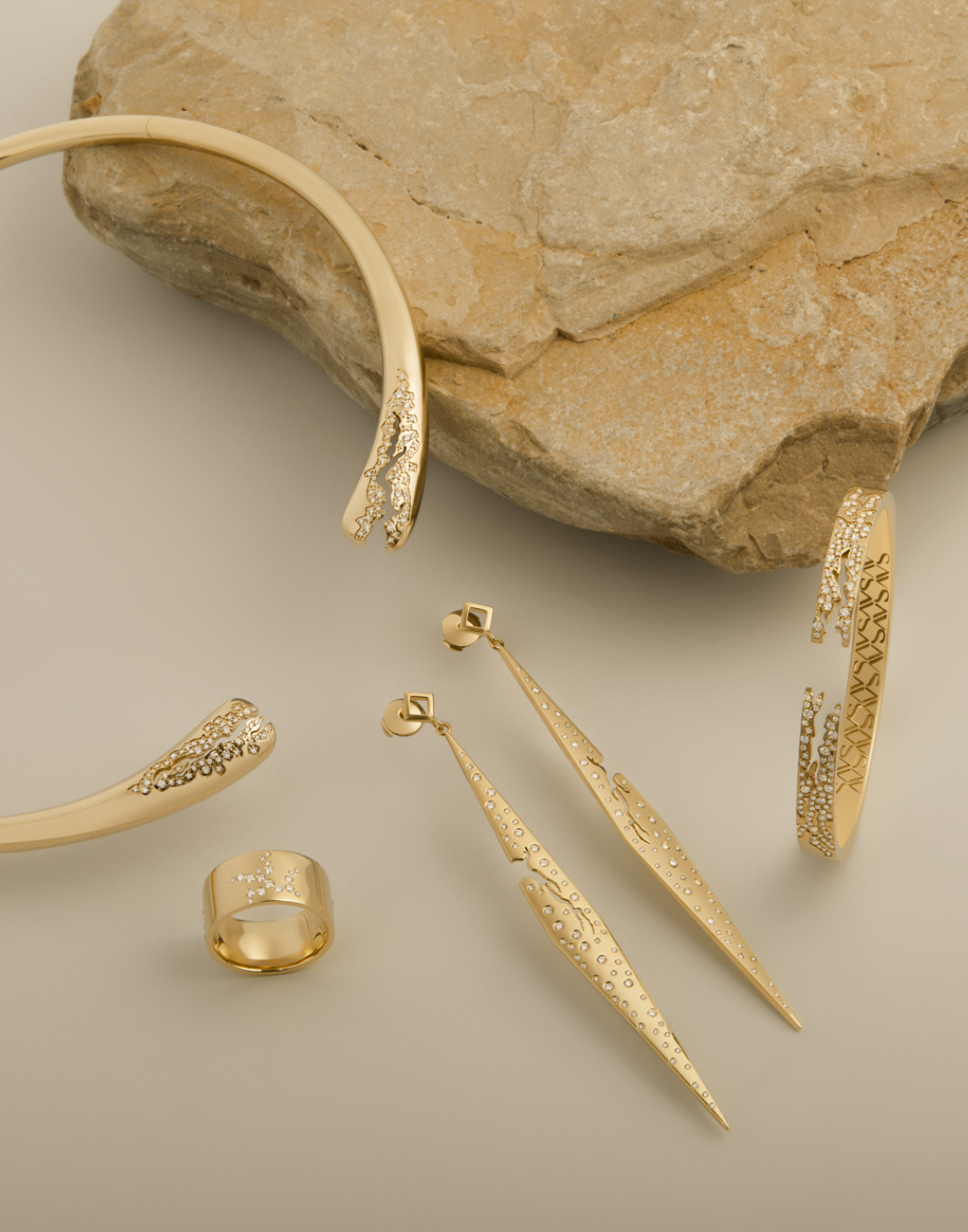 Stylized shot of gold jewelry with a light brown rock