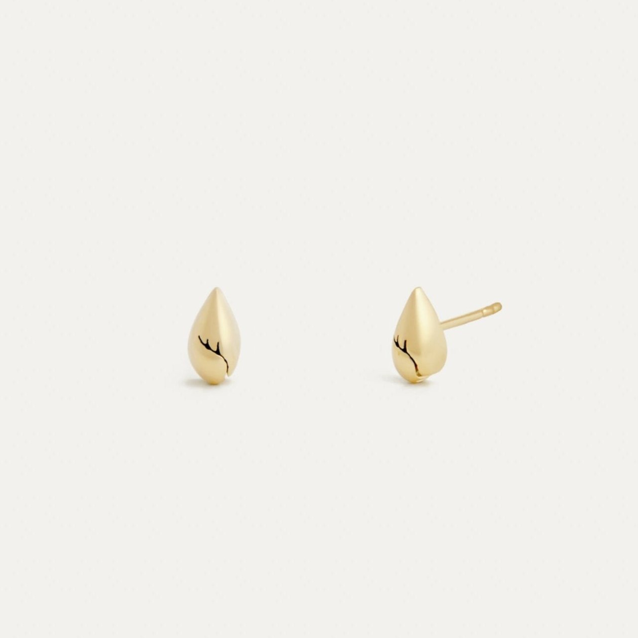 A pair of pear-shaped stud earrings made from recycled gold, with a smooth polished surface, displayed against a white background.