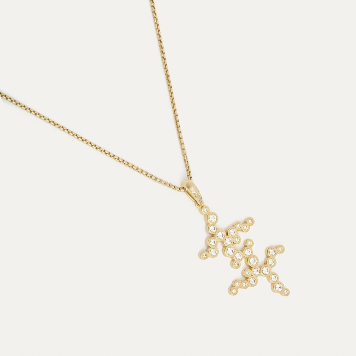 A pendant necklace with a gold chain and a gold pendant featuring a series of bezel-set diamonds.