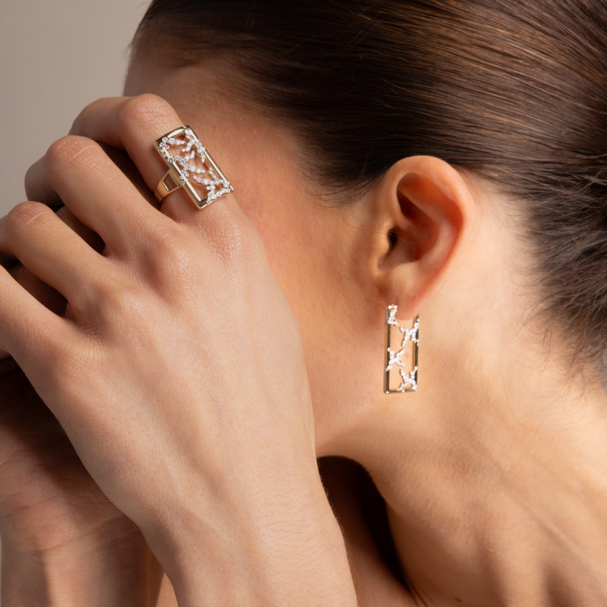 Model wearing the yellow gold Emergence rectangle ring and matching rectangle hoop earrings, each with an openwork lab-grown diamond pattern.