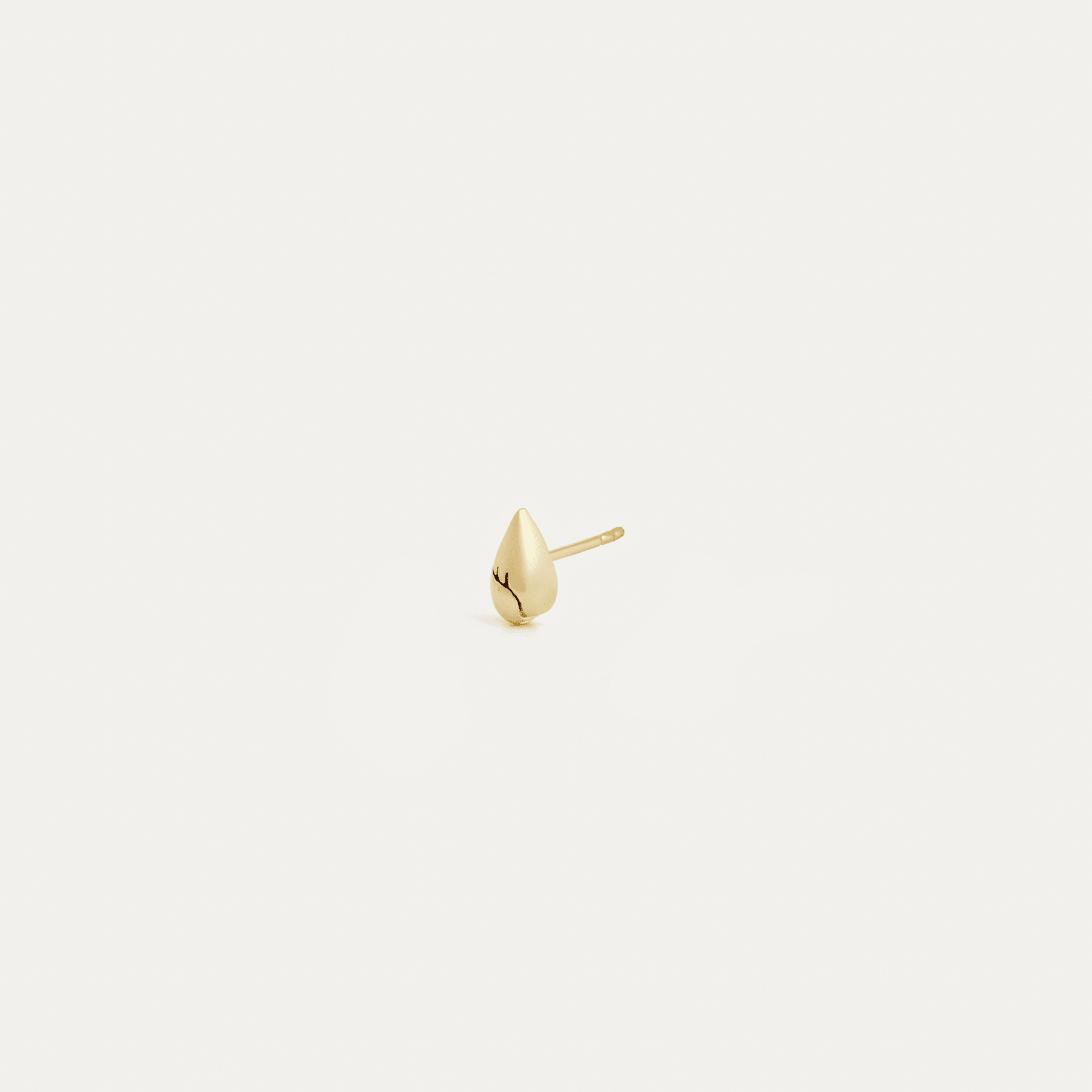 Single 14k yellow gold pear spike stud earring shown at a slight angle, displaying the sculptural convex form, fine crack detail, and straight post.