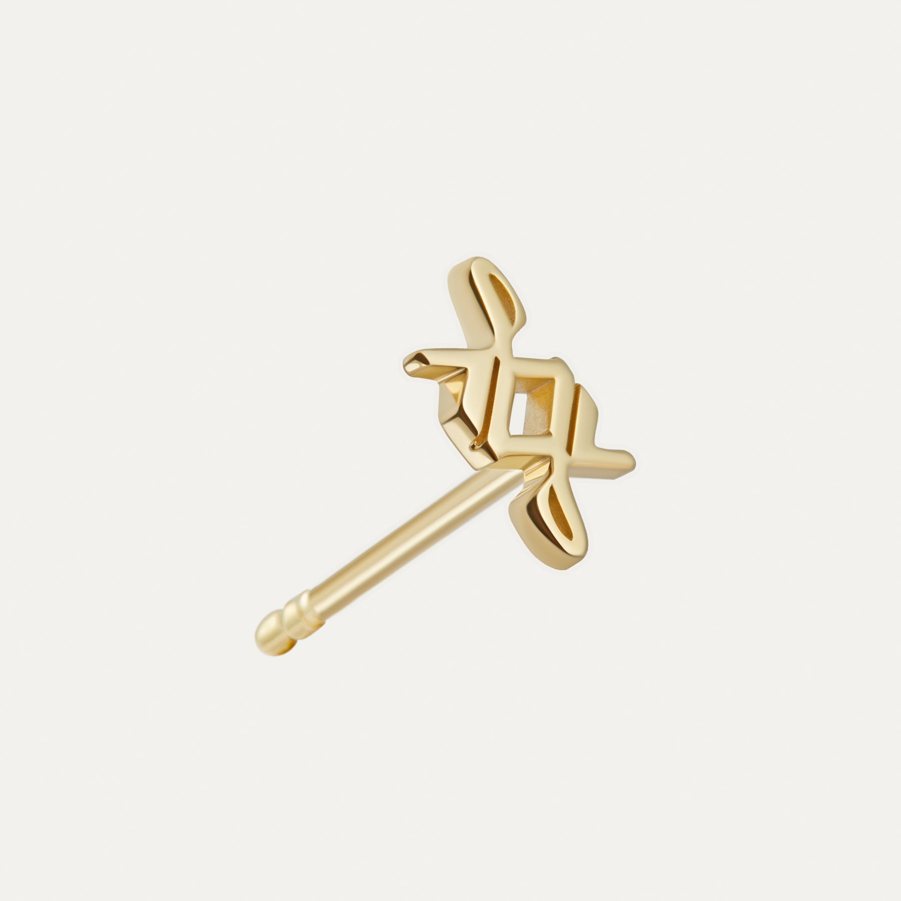 Close-up of a single 14k yellow gold SAV logo stud earring from the back, showing the openwork monogram face and the straight post with notched tip.