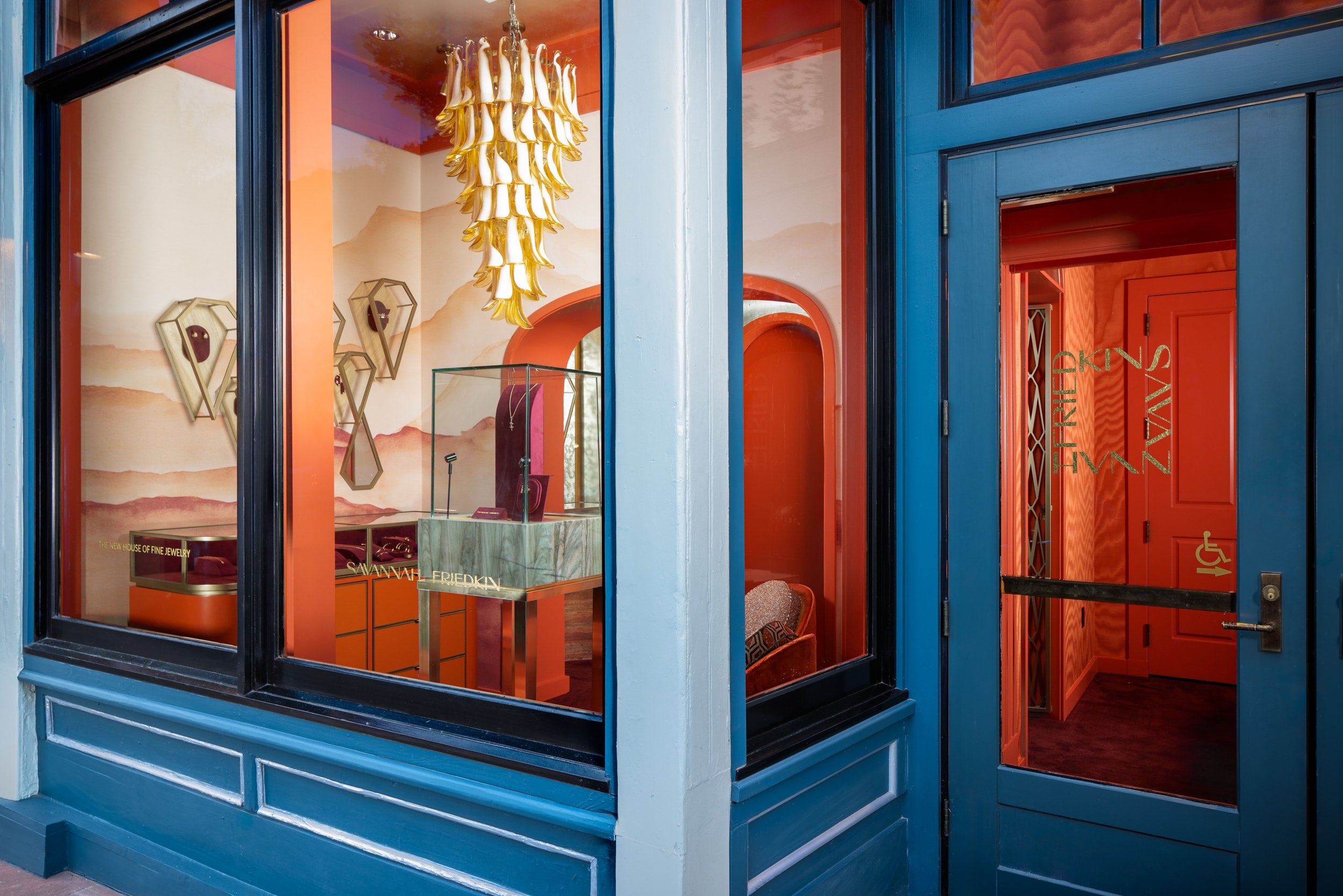 Blue door with glass panels reflecting interior decor, including a chandelier.