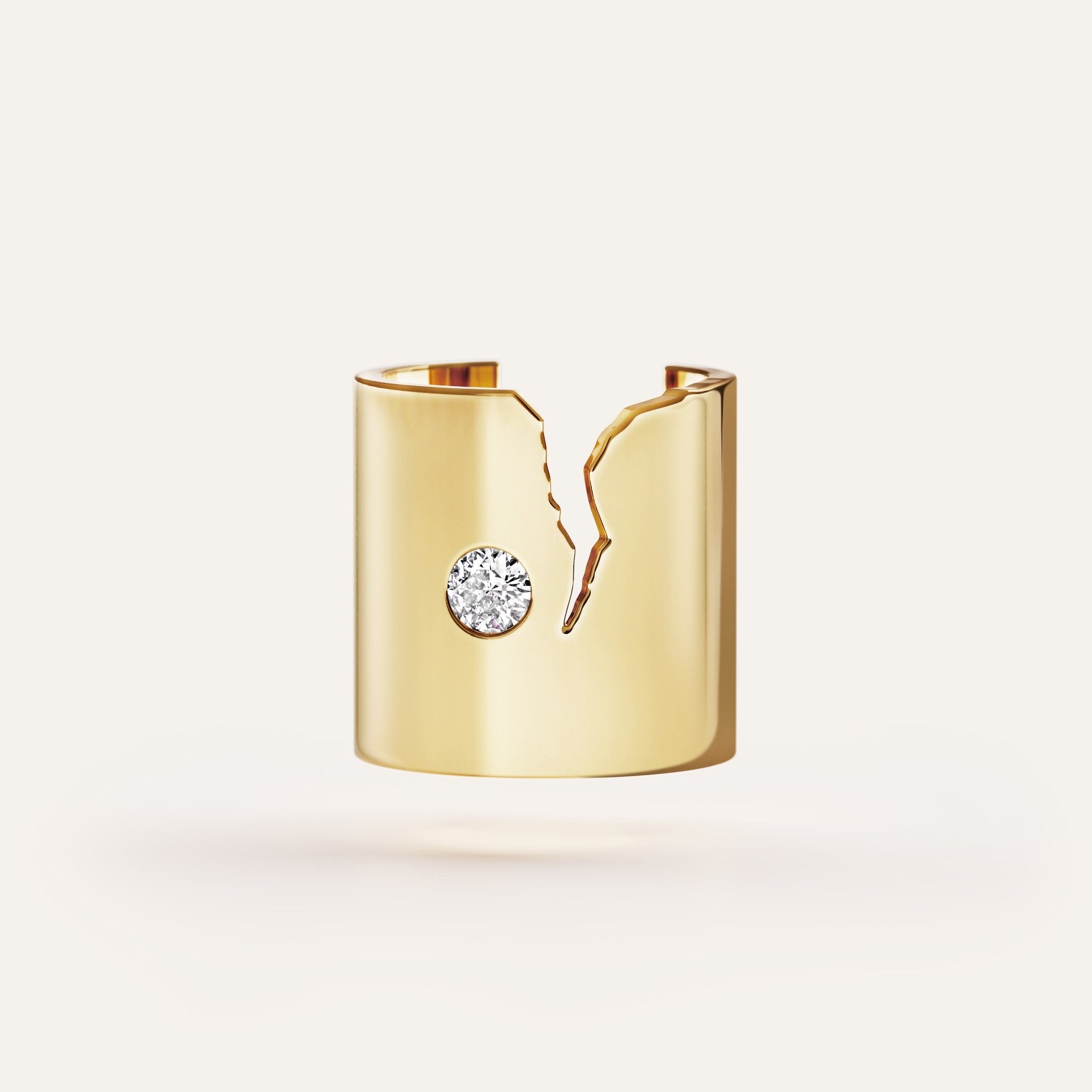 Gold cuff bracelet with a central gemstone on a light beige background