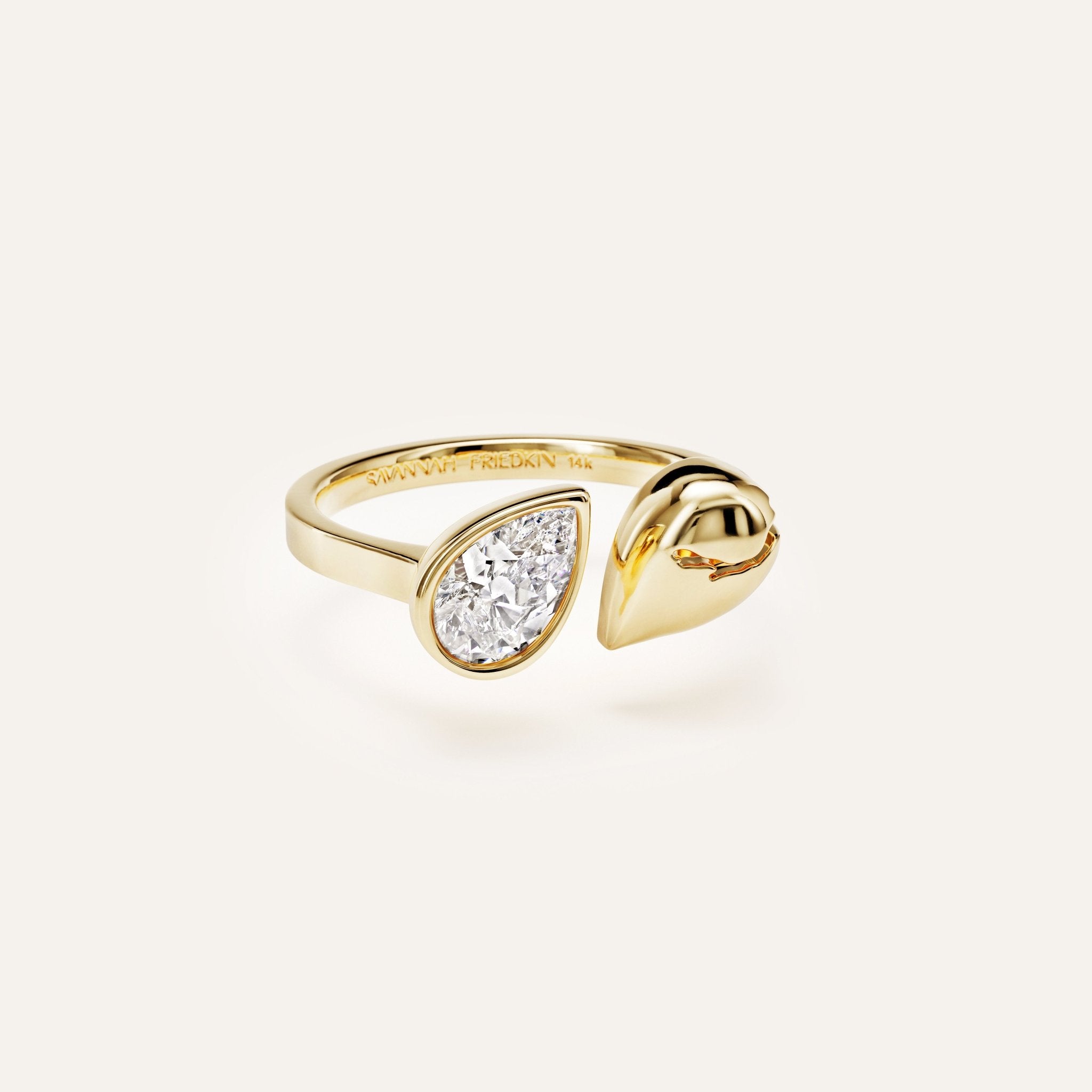 Gold ring with a pear-shaped diamond on a white background