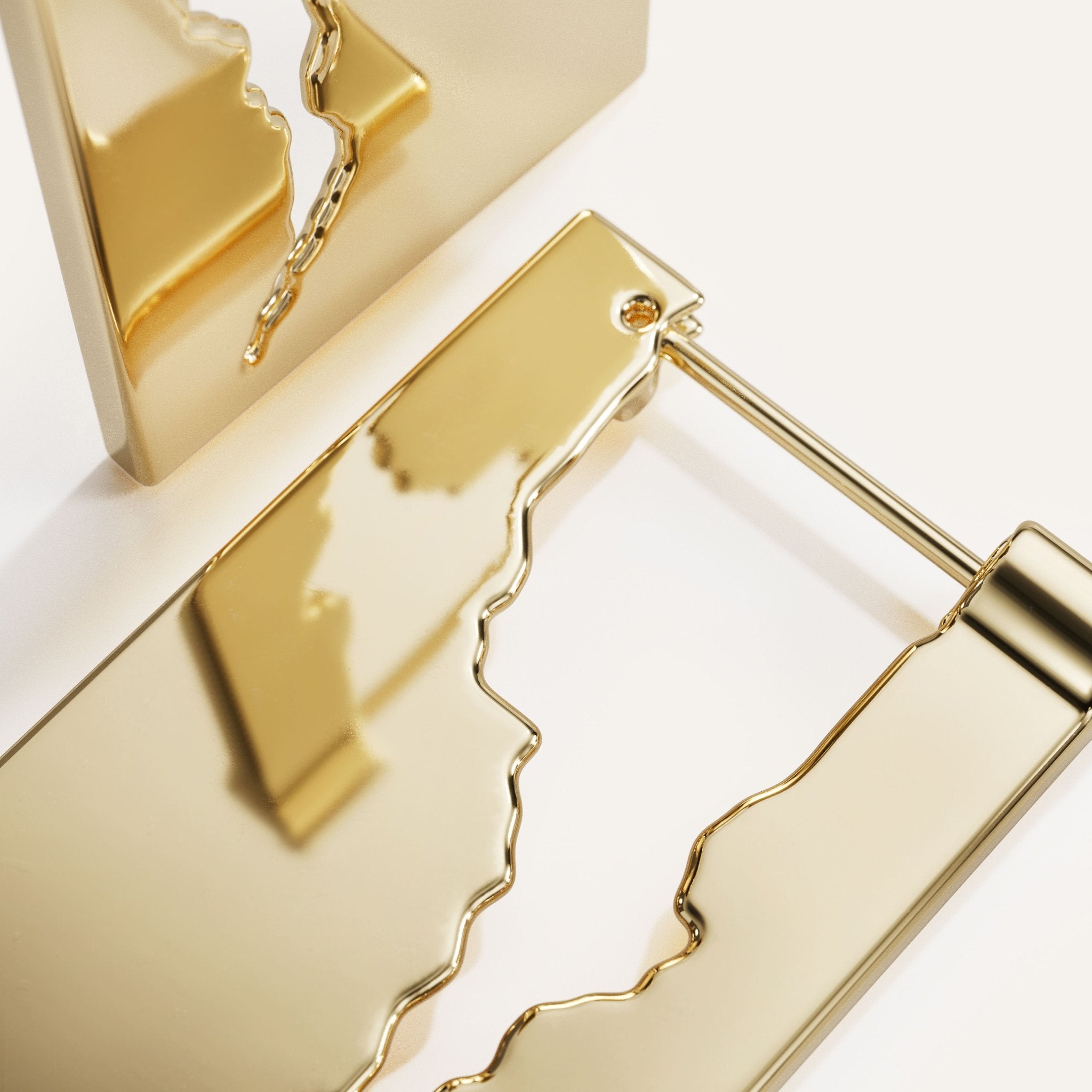 Gold jewelry piece with a cracked design on a white background