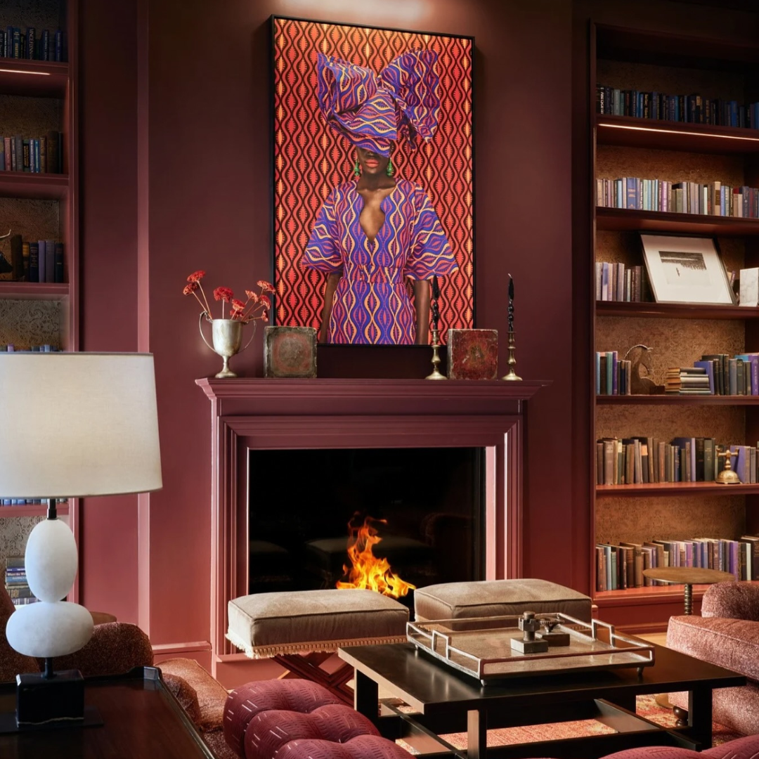 Living room with fireplace, books, and a painting of a woman in traditional attire.