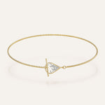 Gold bracelet with a triangle-shaped clasp on a light beige background