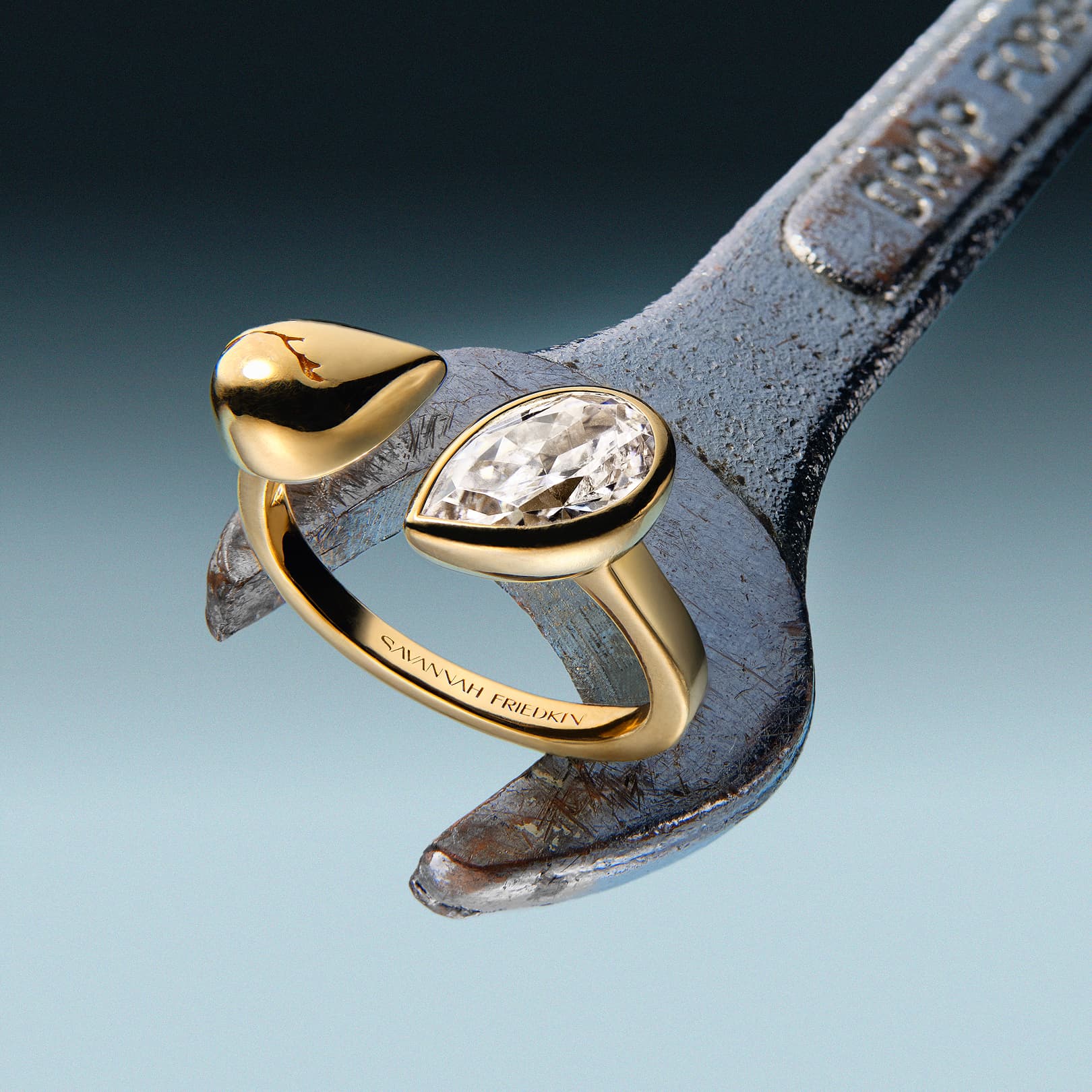 Gold ring with a diamond on a wrench against a gradient background.