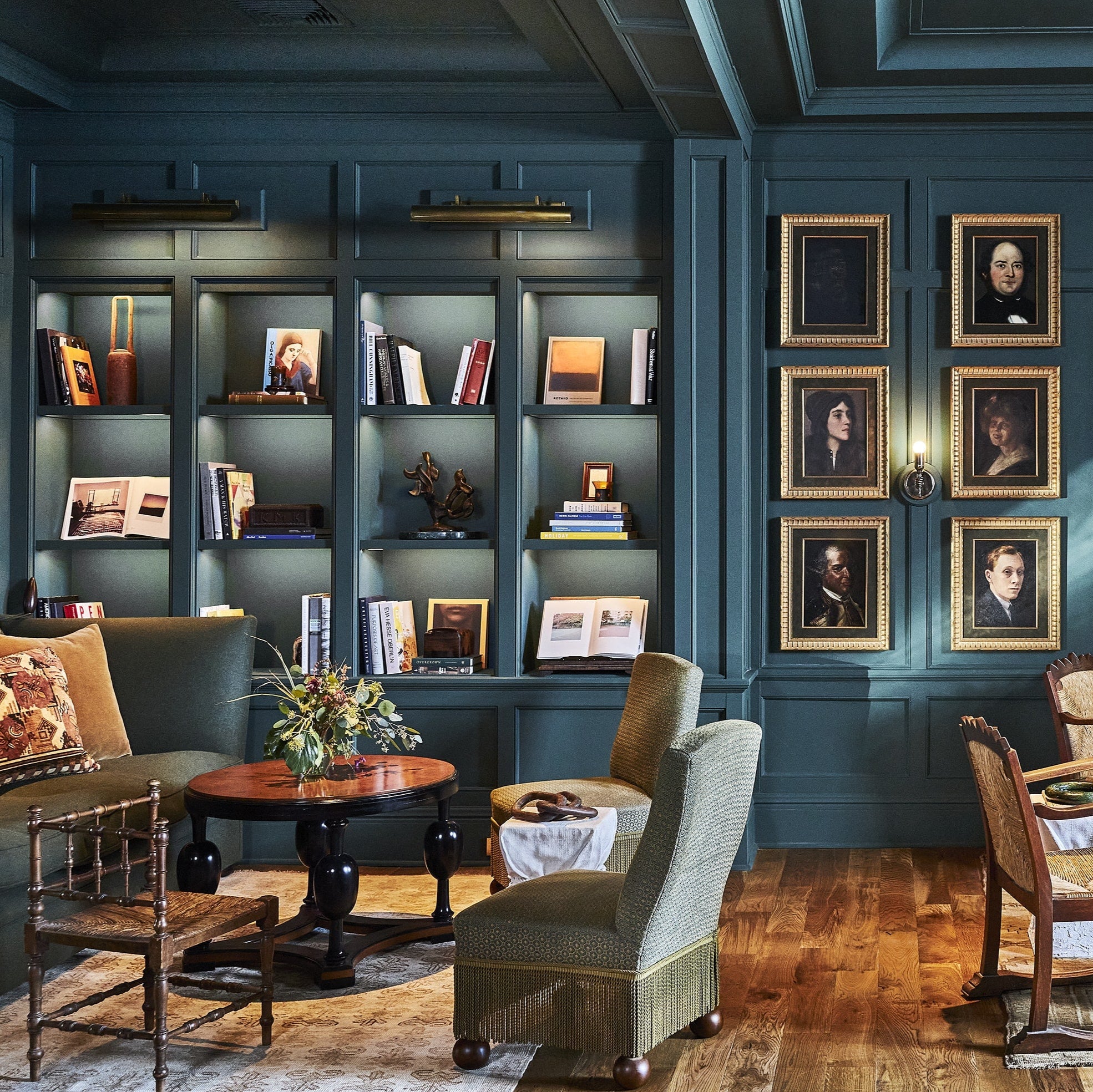 Luxurious interior with dark blue walls, bookshelves, and framed pictures.