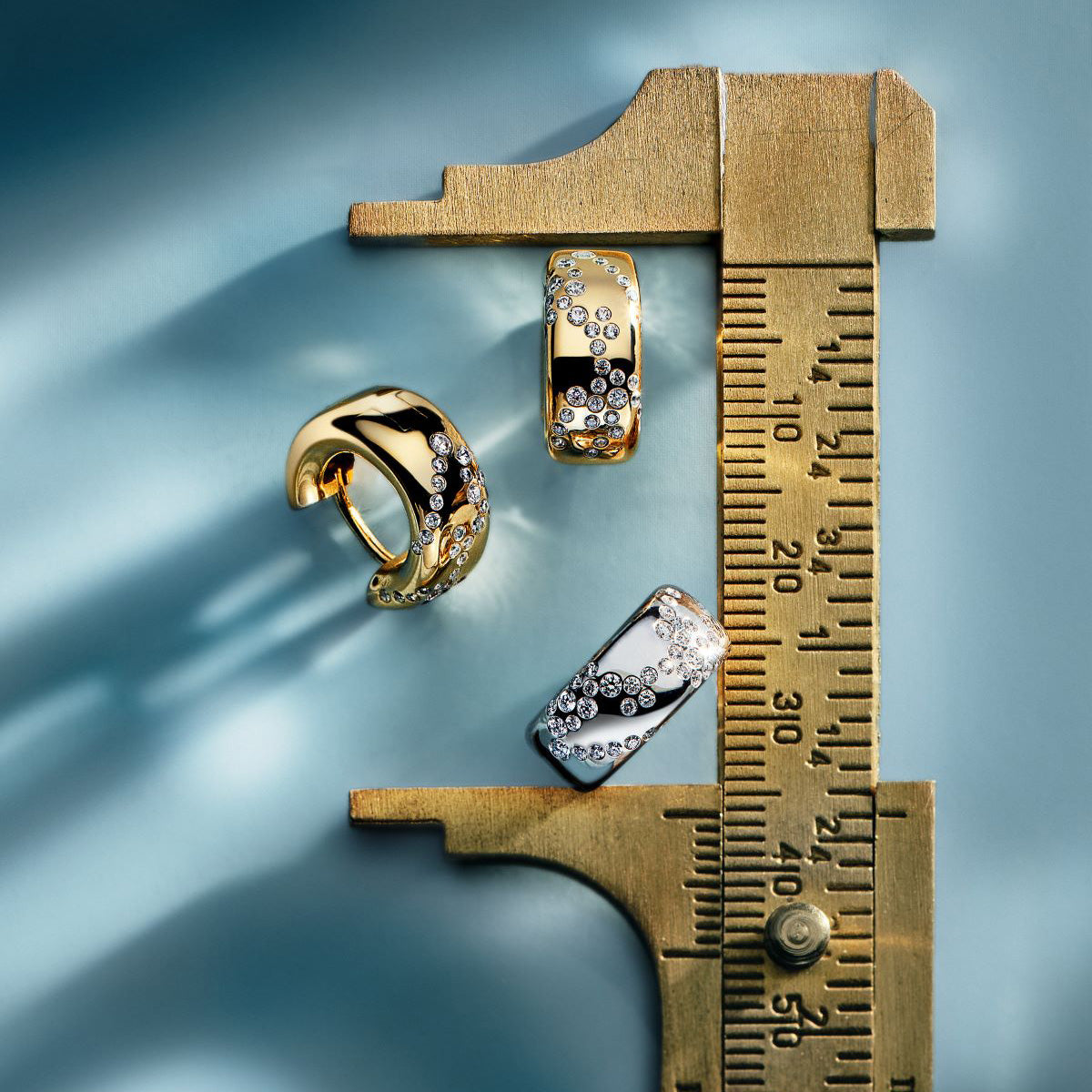 Three gold rings with lab grown diamonds and a caliper
